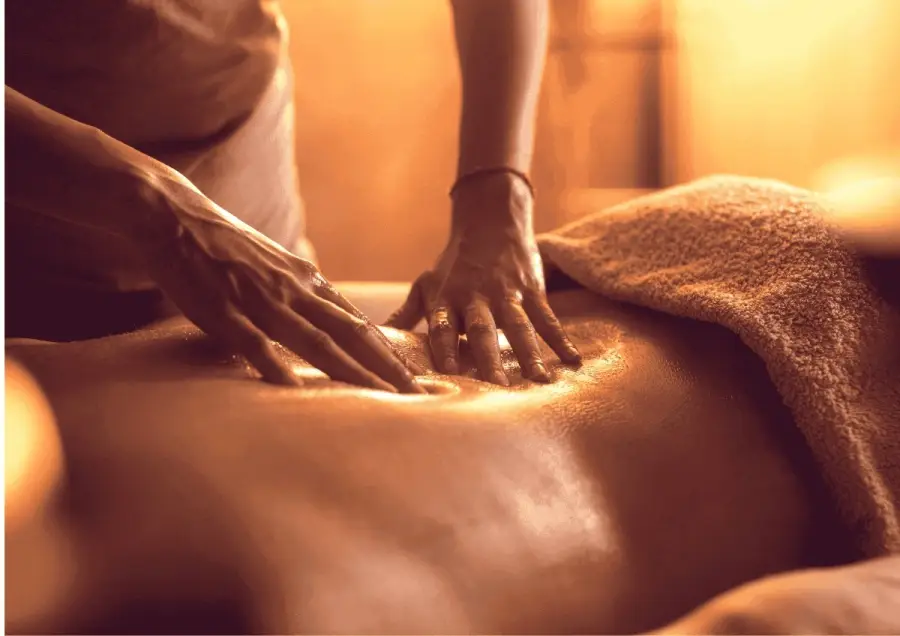 Hands giving a full body massage with warm oil